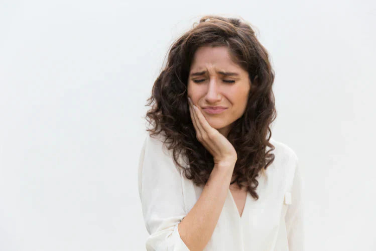 Uma mulher a segurar o queixo por causa de uma dor de dentes.